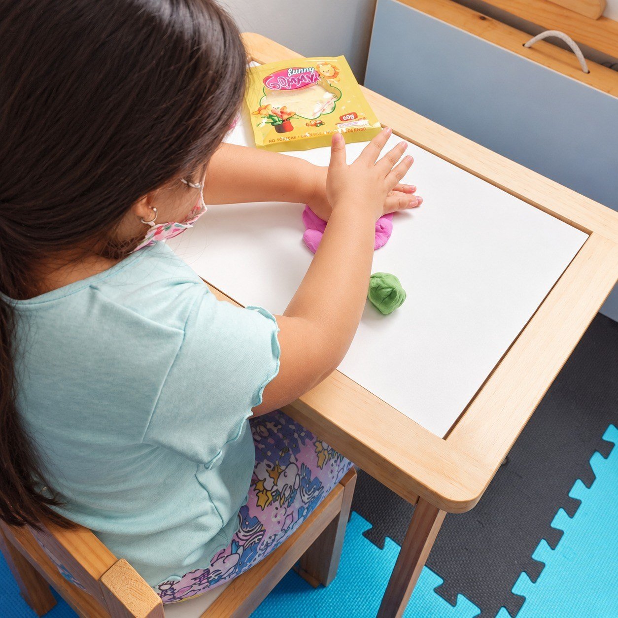 Niña trabajando motricidad fina con material moldeable en mesa terapéutica