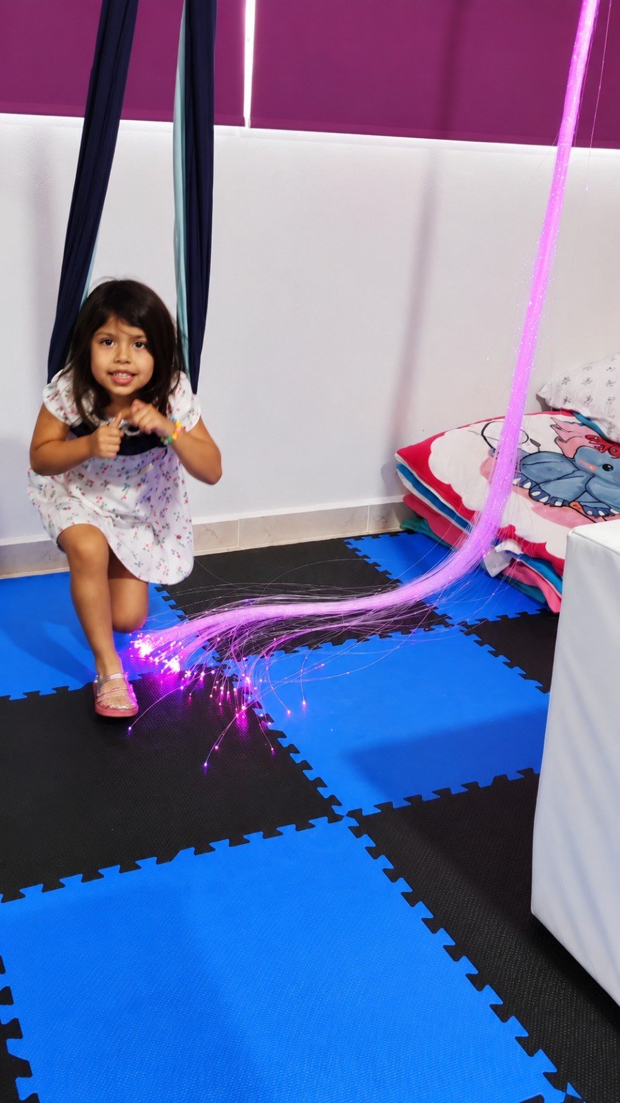 Niña explorando fibras ópticas luminosas para atención, curiosidad y autorregulación visual