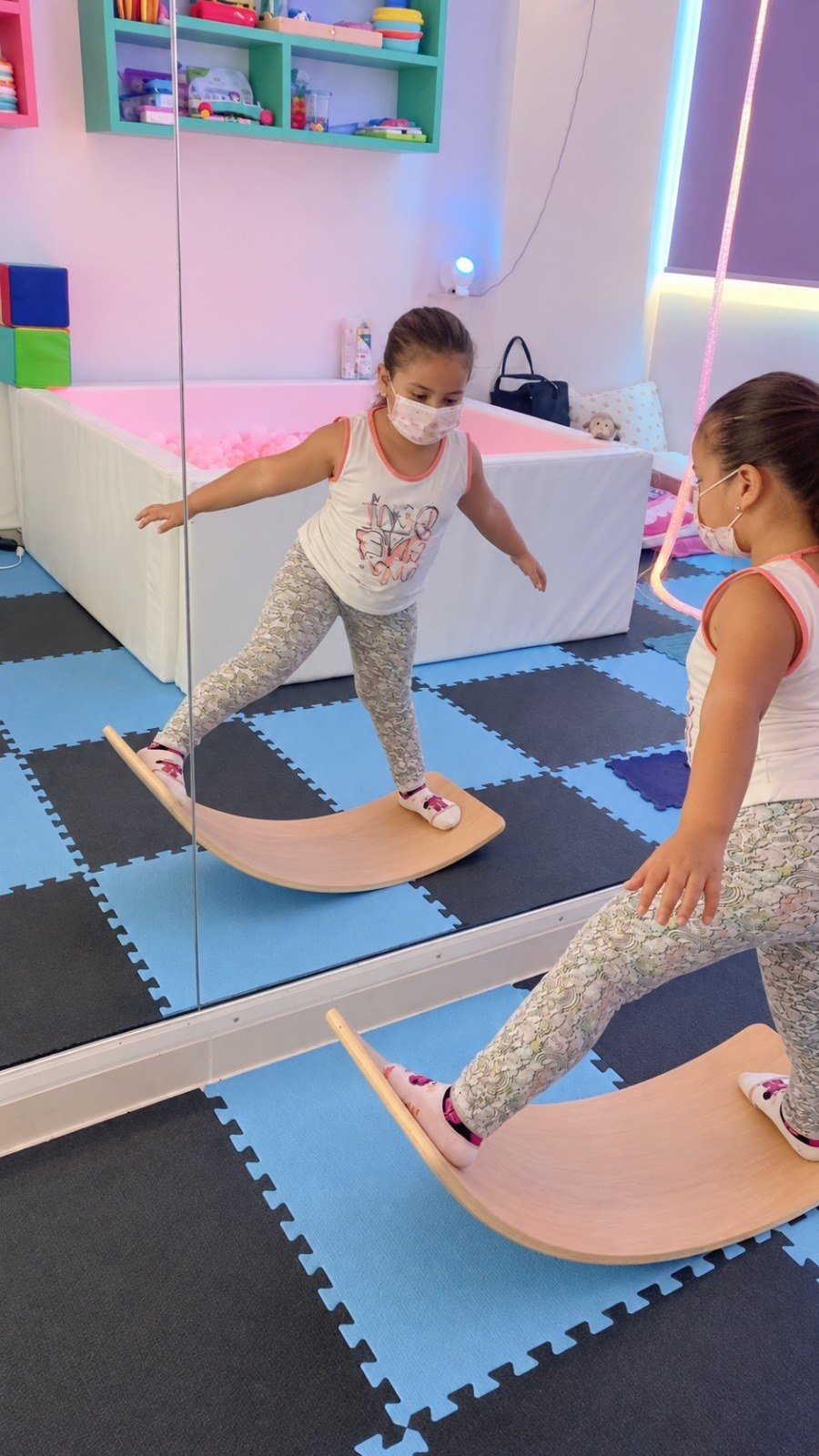 Niña trabajando equilibrio, coordinación corporal y control postural en tabla curva